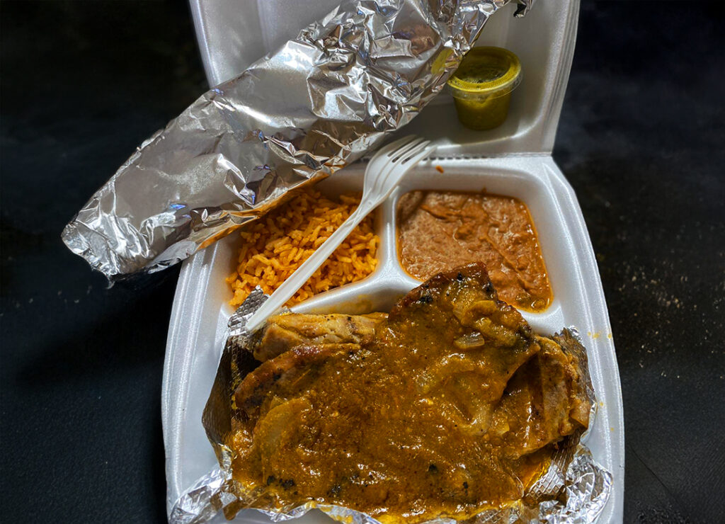 To-go plate of Chuletas Puerco Salsa with refried beans and rice