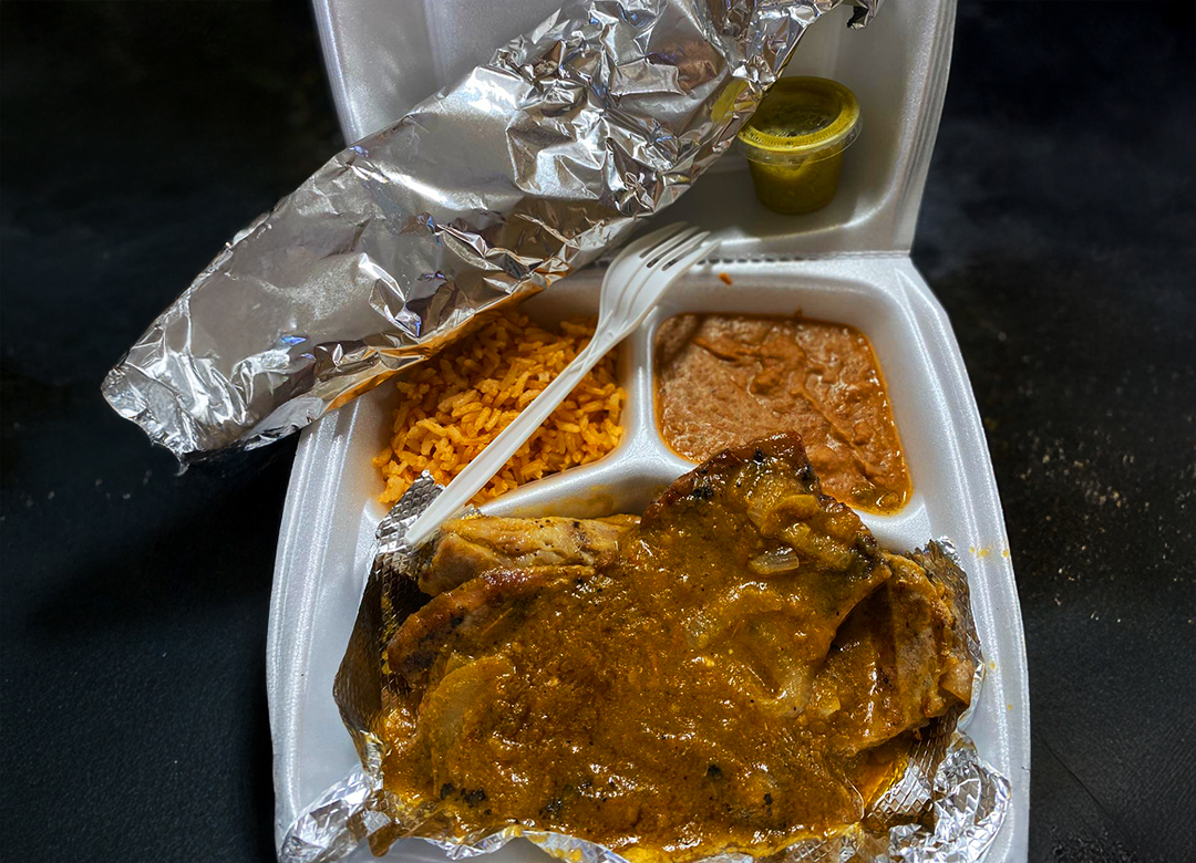 To-go plate of Chuletas Puerco Salsa with refried beans and rice