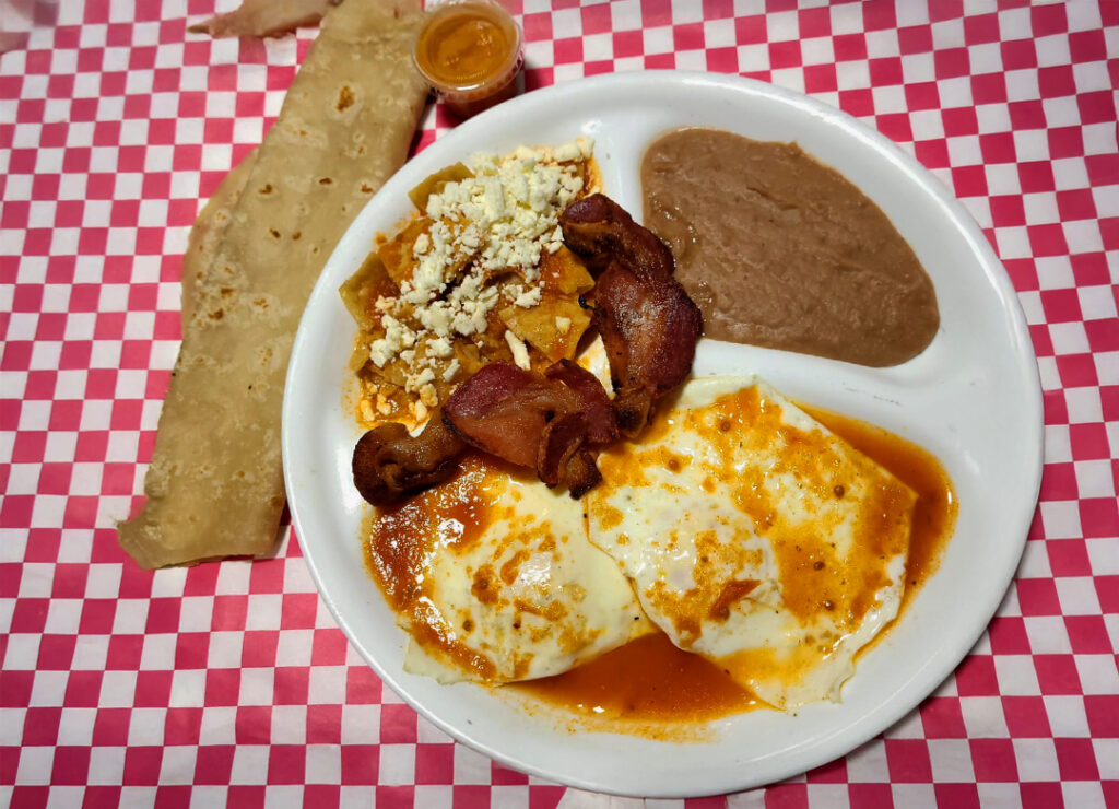 sunny side up eggs in salsa, refried beans, rice, chilaquilles, and a flour tortilla